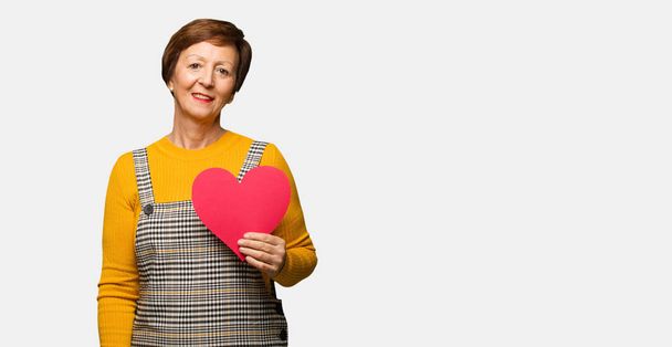 Middle aged woman celebrating valentines day cheerful with a big smile - 写真・画像