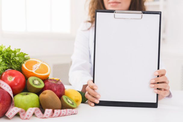 Mulher nutricionista mostrando área de transferência em branco no escritório
 - Foto, Imagem