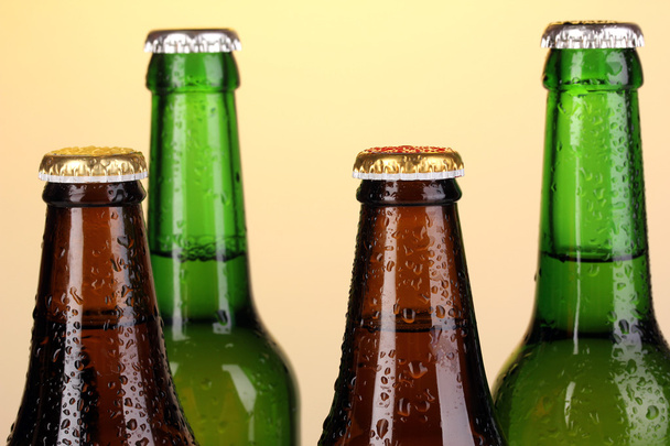 Botellas de cerveza de vidrio de color sobre fondo amarillo
 - Foto, Imagen
