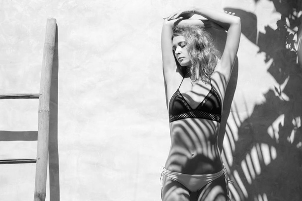 Black and white portrait of woman in bikini leaning on the wall - Photo, Image