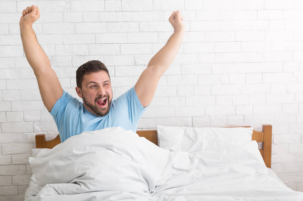 Man waking up in morning, stretching and yawning - Фото, изображение