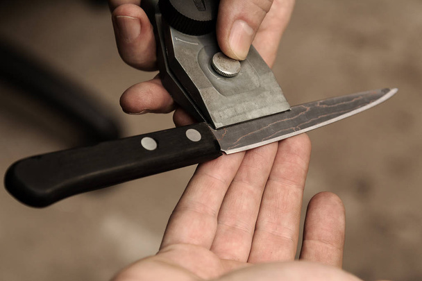 The master checks the sharpening of a knife from Damascus steel - Photo, Image