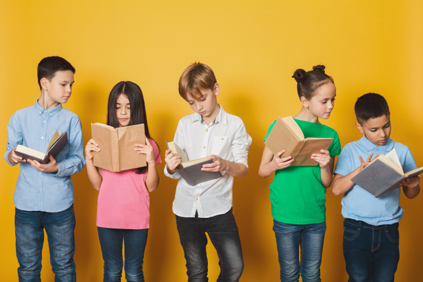 Розумні діти читають книги біля жовтої стіни
 - Фото, зображення