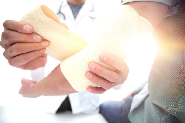 Orthopedist applying bandage onto patients hand in clinic - Foto, Bild