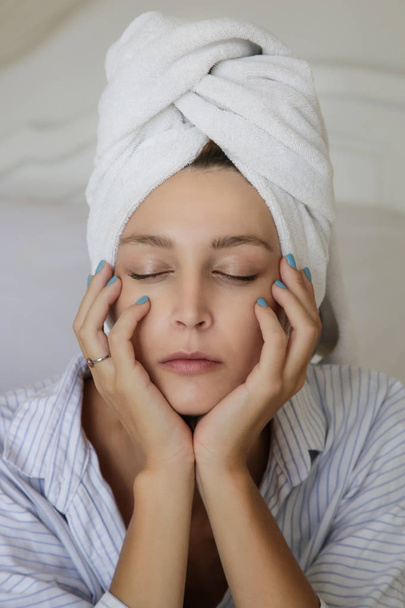 Vrouw in bed, gewikkeld in een handdoek, na douche - Foto, afbeelding