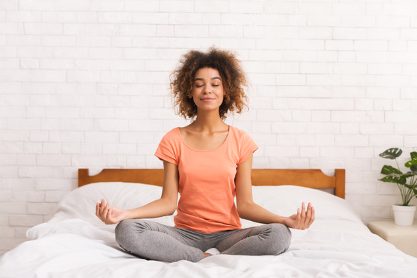 Meditation. Frau sitzt in Lotus-Pose auf Bett - Foto, Bild