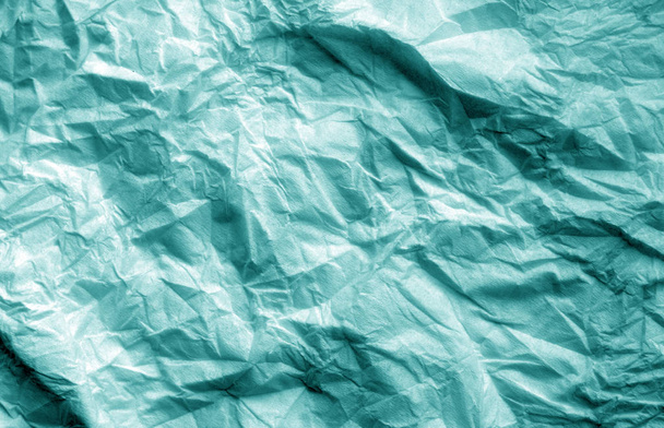 Crumpled sheet of paper in cyan color. Abstract background and texture for design. - Photo, Image