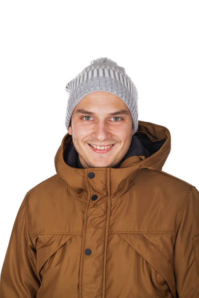 Handsome young man wearing a light brown winter parka jacket - smiling to the camera on isolated background - Fotó, kép
