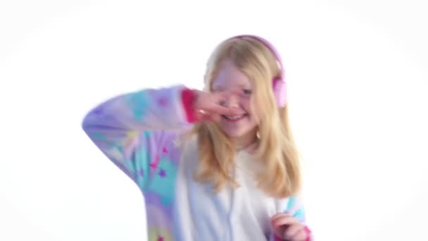сучасна мода - красива блондинка слухає музику з навушниками і танцює на білому тлі в піжамі кігурумі - ізольована на білому
 - Кадри, відео