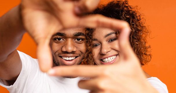 schwarzer Mann und Frau zeigen Rahmenschild mit Händen - Foto, Bild