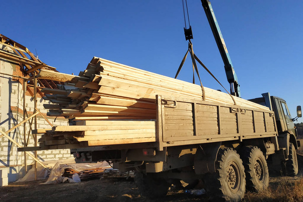 Со стороны грузового крана разгрузить доски для строительства дома 2019 года
 - Фото, изображение