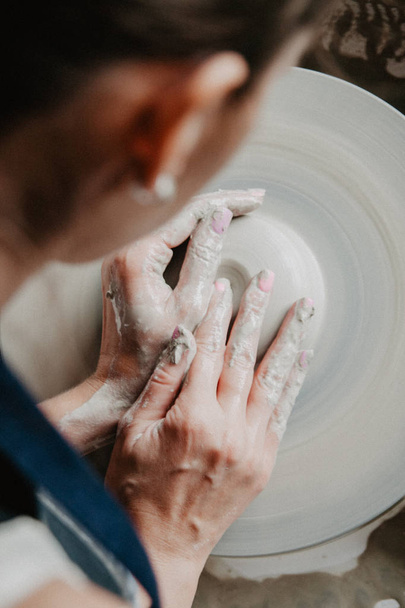 Creating a jar or vase of white clay close-up. Woman hands making clay jug. - Фото, зображення