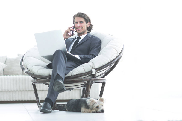 business man talking on a smartphone sitting in the living room - 写真・画像