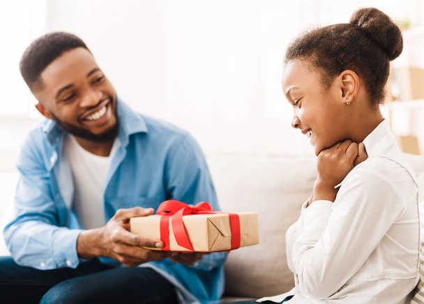 Афро-американский отец дарит подарок дочери дома
 - Фото, изображение