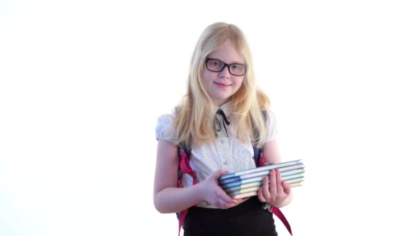 mooie schoolmeisje met een school rugzak en een bril poseren in de studio op een witte achtergrond - Video