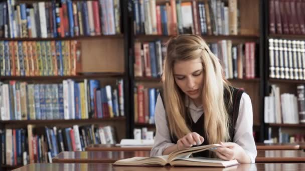 Kaunis tyttö opiskelija lukee kirjaa kirjastossa
 - Materiaali, video