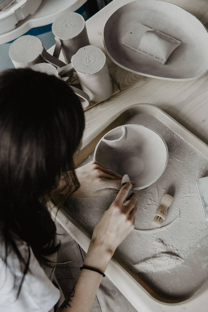 Woman making pottery. Close-up of process of sanding clay plate - Valokuva, kuva