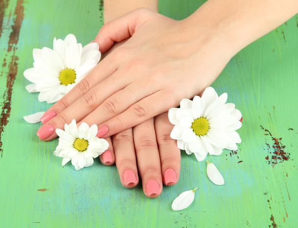 Woman hands with pink manicure and flowers, on color background - Photo, Image