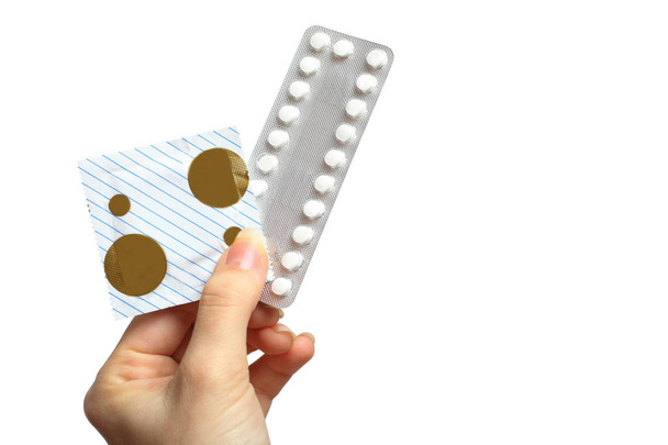 Vrouw holding in handen mondelinge contraceptieve pillen en condoom, geïsoleerd op wit. Concept gynaecologie, seksuele voorlichting. - Foto, afbeelding