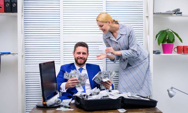 Business, people and finances concept. Falling pennies. Happy and excited man sitting at table covered with money and rejoices with girl secretary. - Fotografie, Obrázek