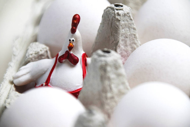 Close-up op Pasen haan decoratie zitten in een doos, omgeven door witte eieren - Foto, afbeelding