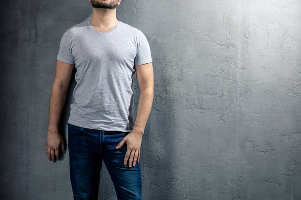 Joven hombre sano con camiseta gris sobre fondo de hormigón con copyspace para su texto. Imagen sin cara de modelo
. - Foto, imagen