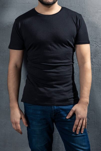 Young healthy man with black T-shirt on concrete background. Picture without model face. - Photo, Image