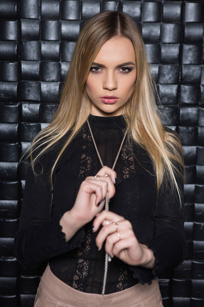 Portrait de jeune femme posant en chemisier noir et chaîne en argent
 - Photo, image