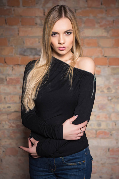 young blonde woman posing against brick wall background - Foto, afbeelding