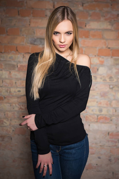 junge blonde Frau posiert vor Backsteinmauer-Hintergrund - Foto, Bild