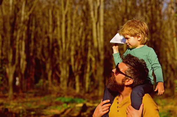 Father hold little son on shoulders with love. Loving father give child piggyback in park, love concept. Friends come and go, but family is always there. - Fotó, kép