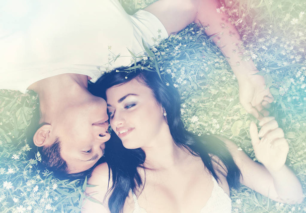Young beautiful couple lying on the grass - Фото, изображение