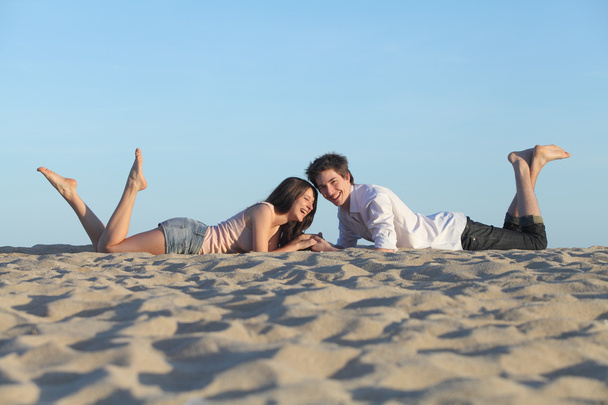 Couple laughing resting on the beach - Fotó, kép