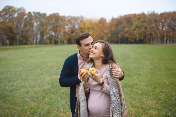 妊娠中の女性のドレスと屋外公園のハグで愛情のある夫  - 写真・画像