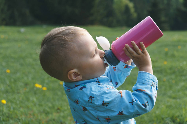 мальчик пьет воду из бутылки на лугу
 - Фото, изображение