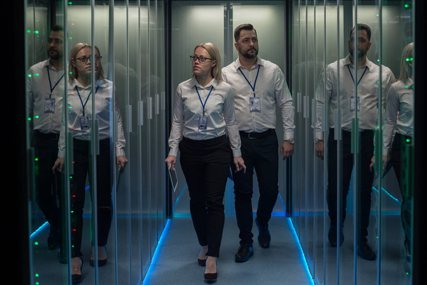 Lavoratori in un data center che camminano tra file di rack server
 - Foto, immagini