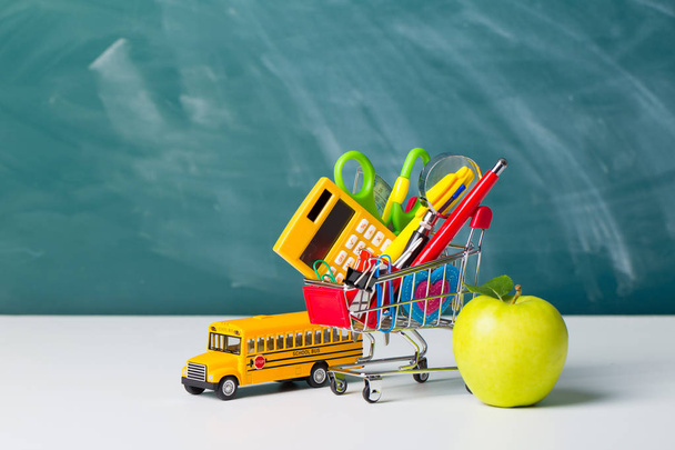 Back to school concept. School supplies, schoolbus and shopping cart with stuff - Φωτογραφία, εικόνα