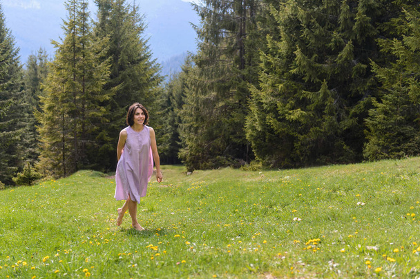 barefooted woman in dress walking on grass at pine forest - Photo, Image
