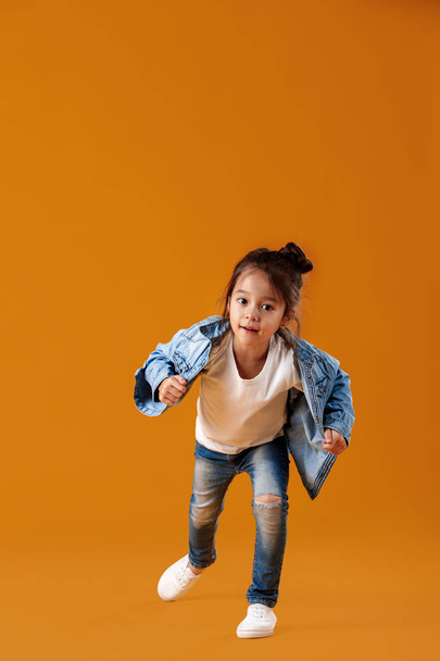 happy little child girl in jeans clothes jumping - Fotografie, Obrázek