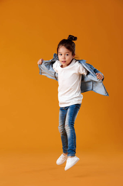 happy little child girl in jeans clothes jumping - Фото, изображение