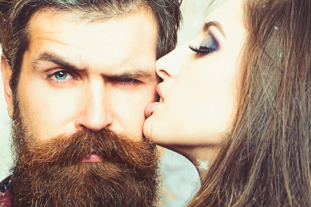 Woman kiss hipster with long beard, love. Sensual woman with makeup skin and bearded man. Couple in love and family concept. Beauty salon and barber shop. Skincare and hair care concept - Foto, immagini
