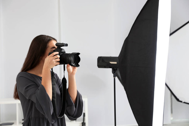 Young woman with professional camera in photo studio - Φωτογραφία, εικόνα