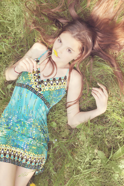 Мрійлива жінка лежить на траві і німій кульбабі
 - Фото, зображення