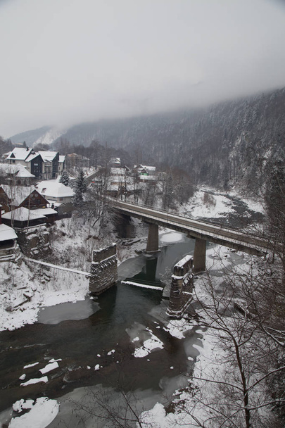 Blick auf Häuser und Eisenbahnbrücke in der Wintersaison in Jaremche, Ukraine  - Foto, Bild