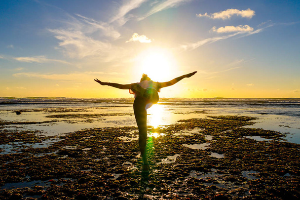 Jeune femme en bonne santé pratiquant le yoga sur la plage au coucher du soleil. Femme de confiance forte sous le coucher du soleil au bord de la mer. Silhouette de jeune femme faisant du yoga sur la plage
. - Photo, image