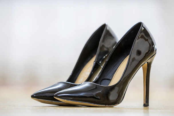 Paire de chaussures féminines noires en cuir vernis à talons hauts à la mode isolées sur fond d'espace de copie légère. Style et mode, concept de chaussures modernes
. - Photo, image