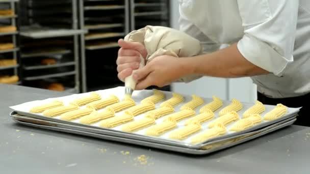 Chef pâtissier professionnel préparant des éclairs extrudant la pâte d'un sac à pâtisserie
 . - Séquence, vidéo