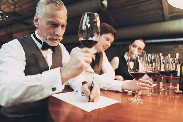 Confident sommelier tasting wine in restaurant. Tasting specialist makes notes. - Foto, Bild