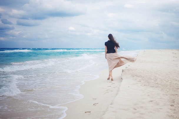 young woman in a long skirt walking on the ocean.  - Fotó, kép