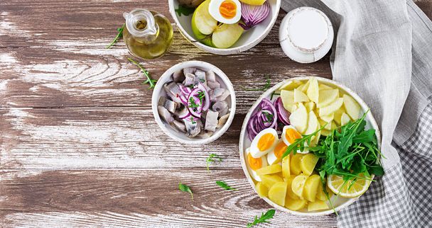 Traditionele salade van gezouten haring filets, eieren, verse appels, rode ui en aardappelen. Koosjer eten. Scandinavische keuken. Bovenaanzicht. Plat leggen - Foto, afbeelding